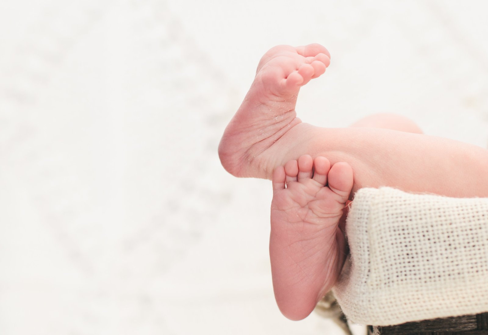 Educadora sentada no chão em diálogo com um bebé, numa sala de creche